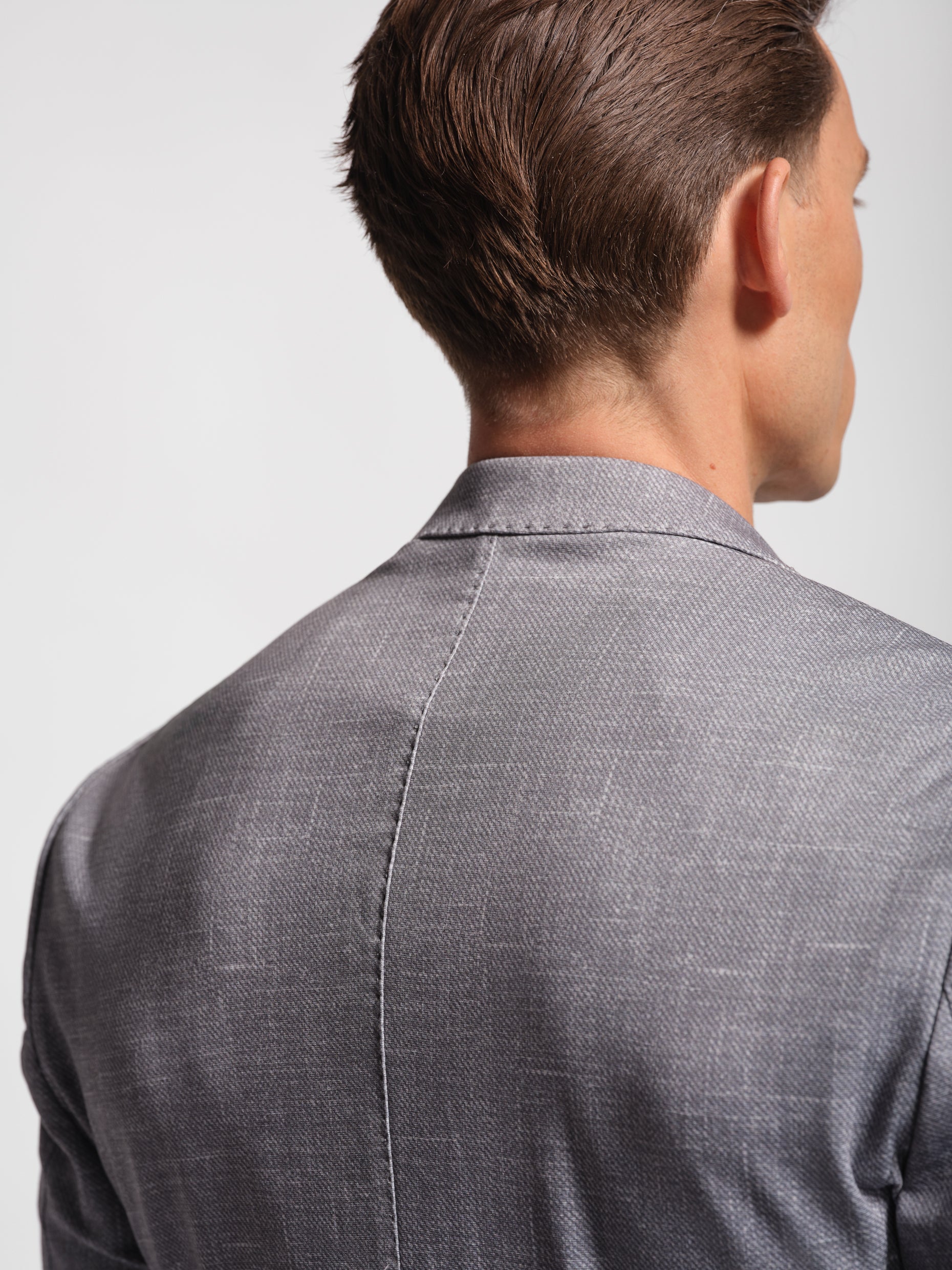 Man wearing a gray stretch jersey suit jacket on a plain background with top stitch