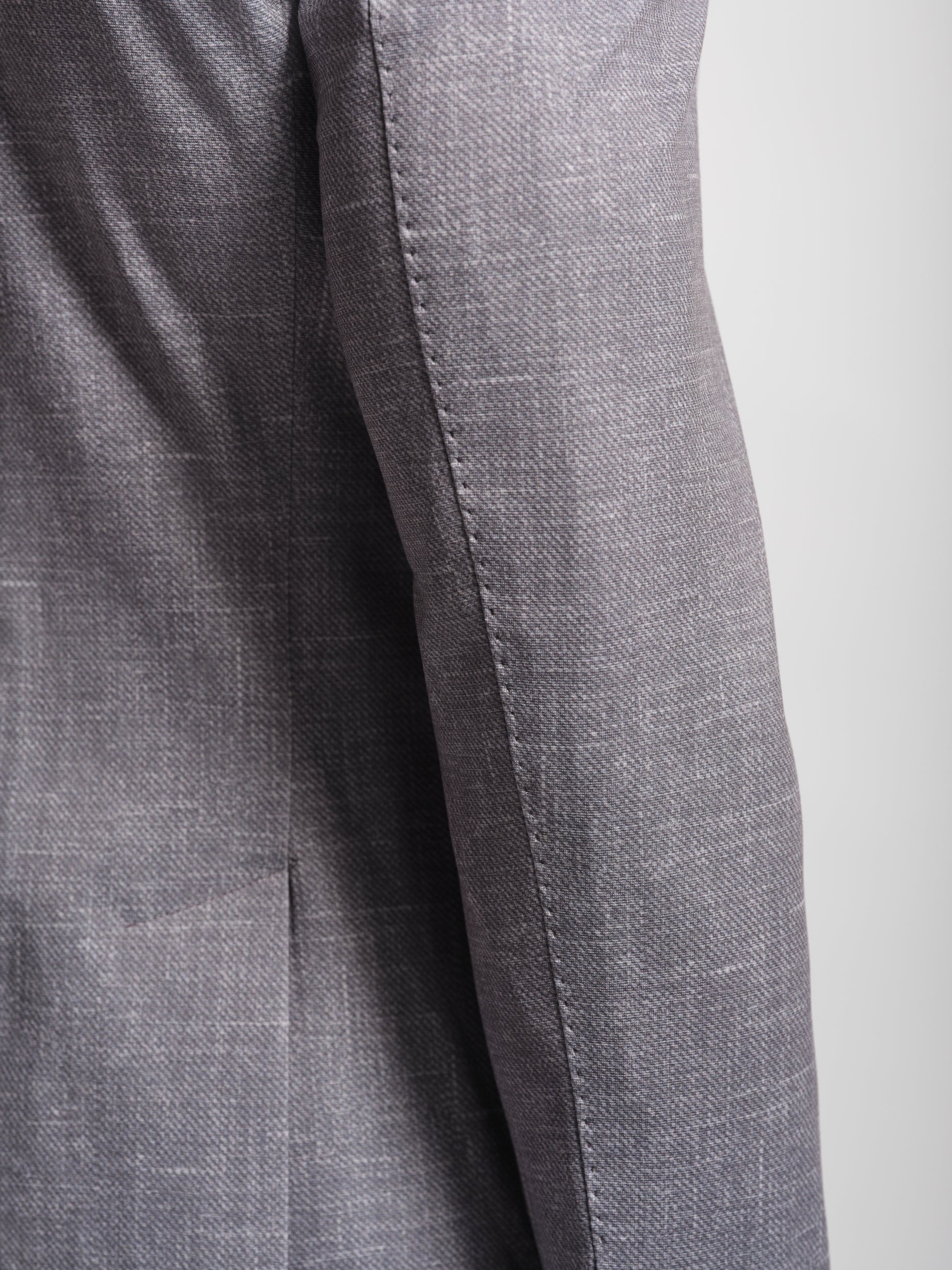 Close-up of a gray suit jacket with topstiching on sleeve stretch jersey