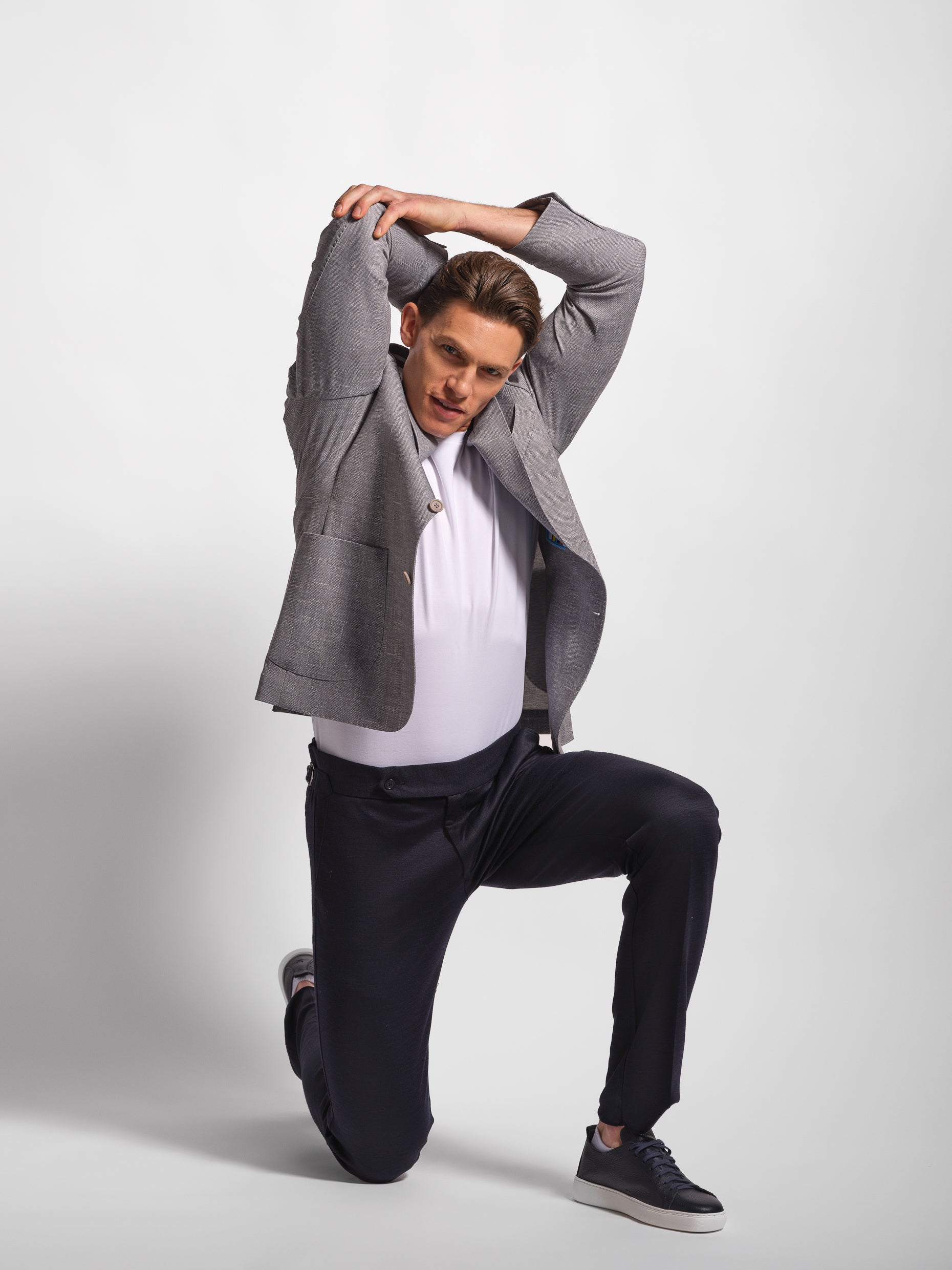 Man in gray blazer and navy pants posing showing comfort and stretch in blazer