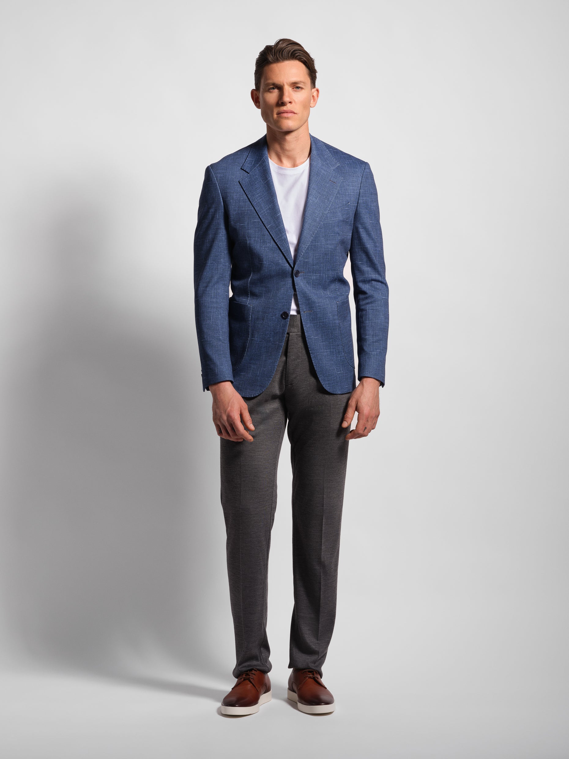 Man in a stretchy, comfort Navy Jersey 2-button blazer jacket over a white t-shirt with navy pants wearing Man Wears Sheep