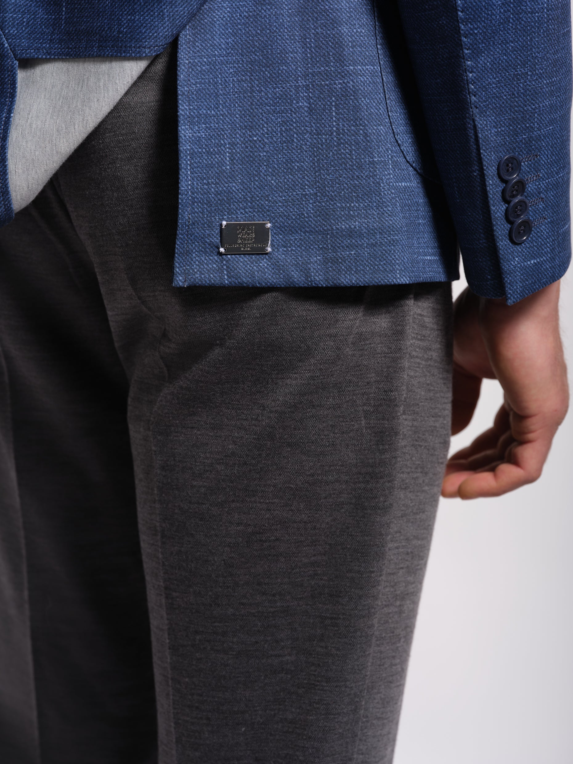 Man in a stretchy, comfortable Navy Jersey blazer jacket showing store metal label over a white t-shirt with navy pants wearing Man Wears Sheep