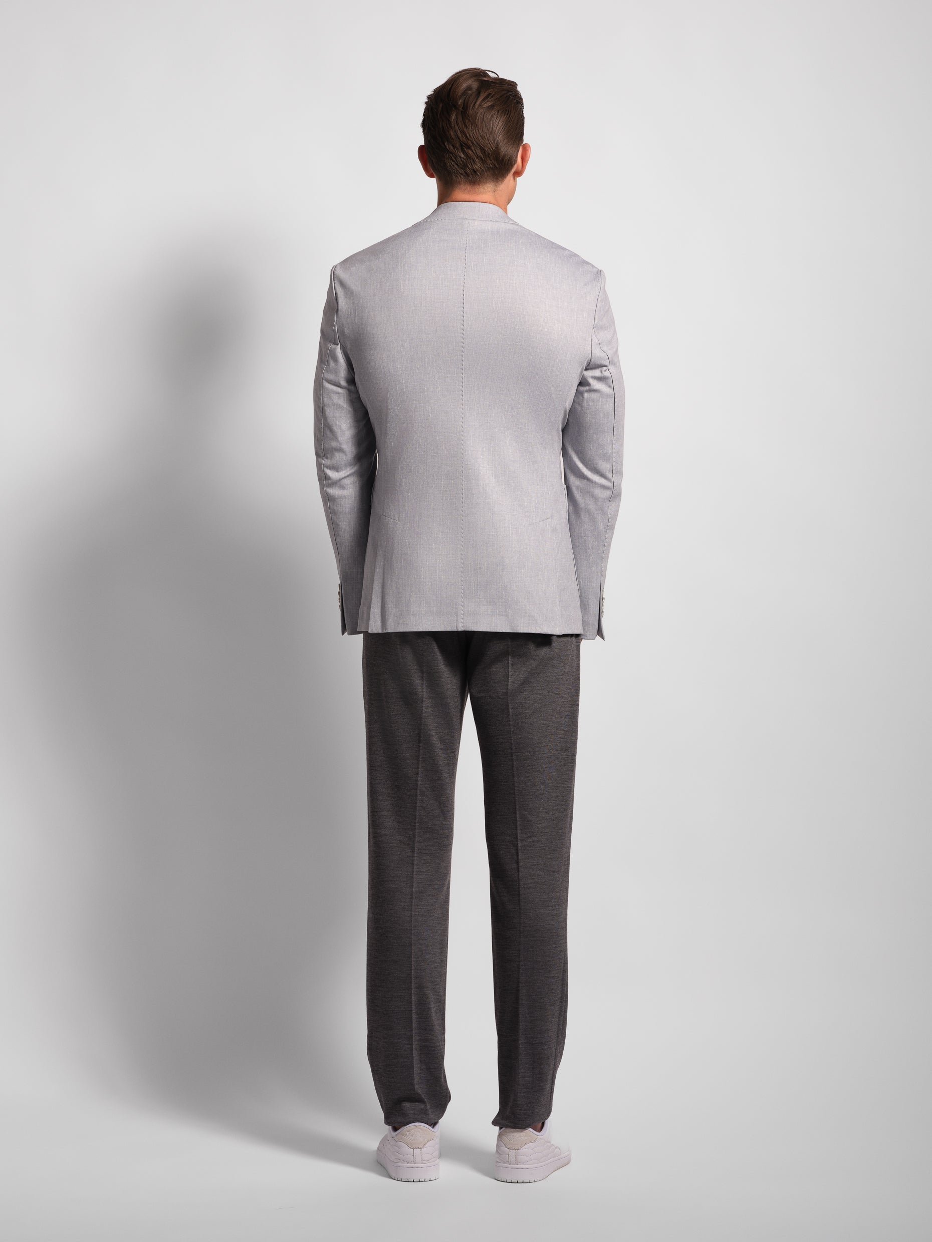 Back of man wearing a gray suit on a plain background with two side vents