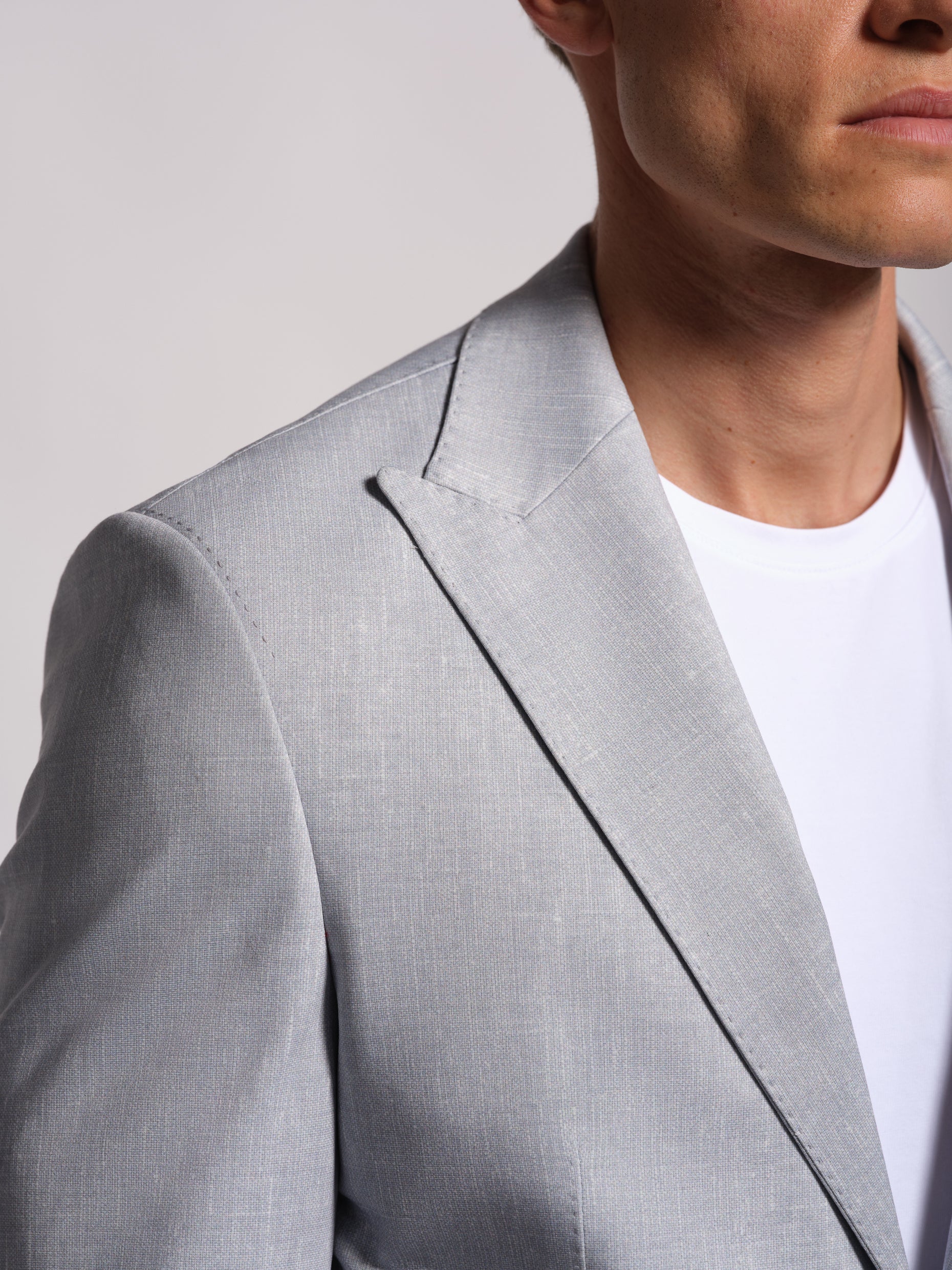 Gray blazer with peak lapel worn by a person on a plain background