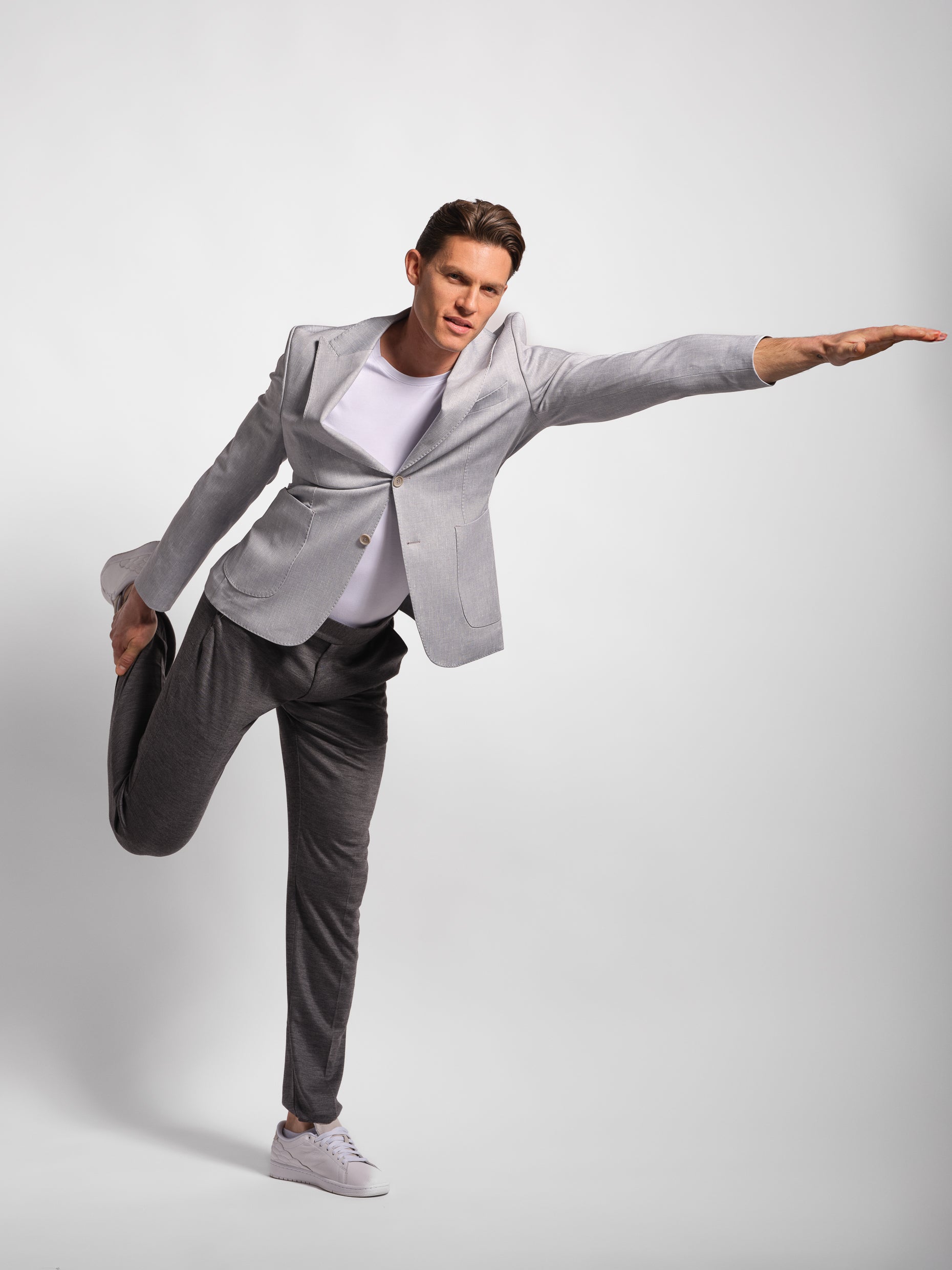 Person wearing a gray blazer thats a stretch and comfortable jacket and white shirt on a plain background