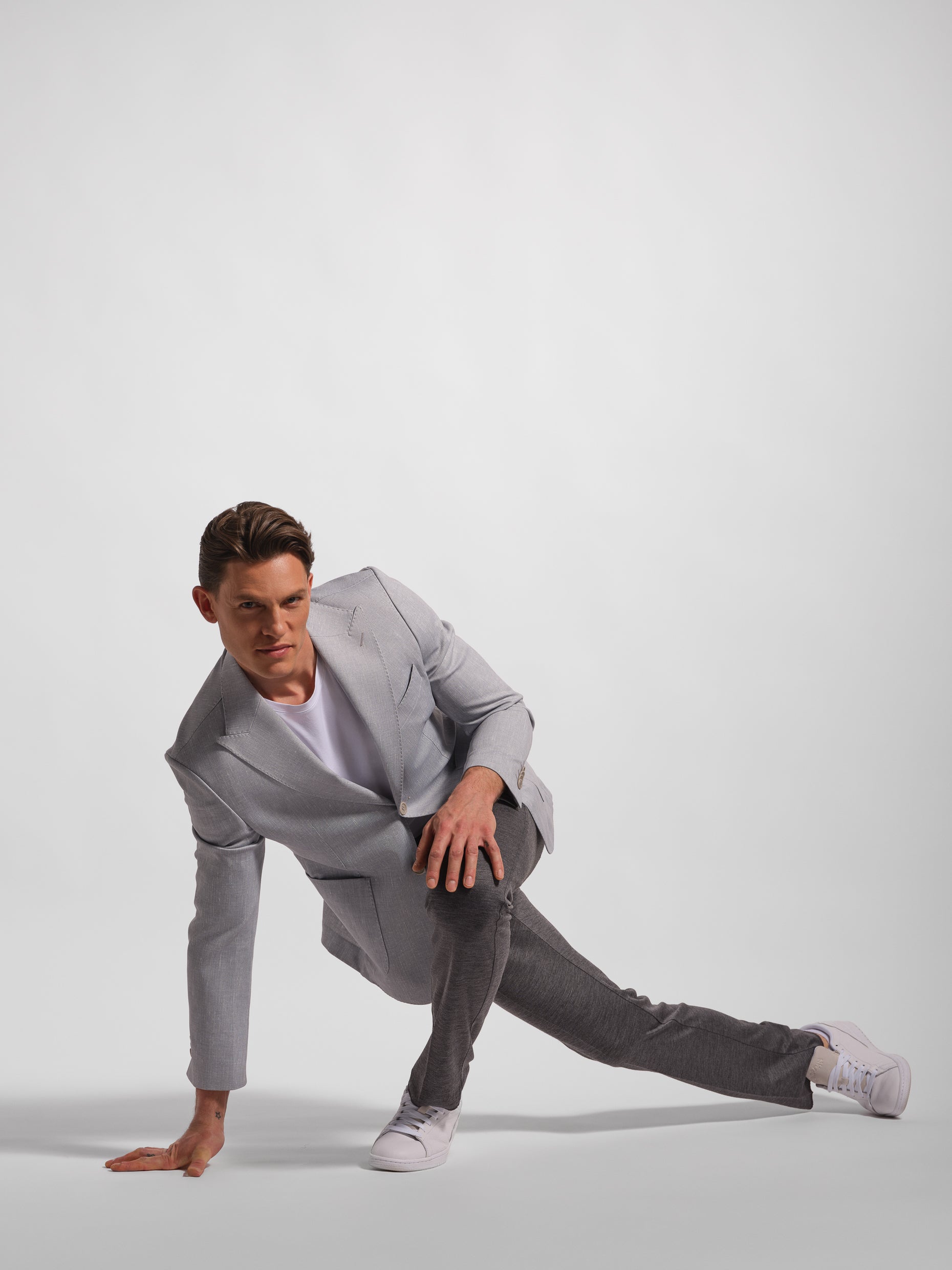 Man in a gray a stretch and comfortable jacket suit posing on a white background