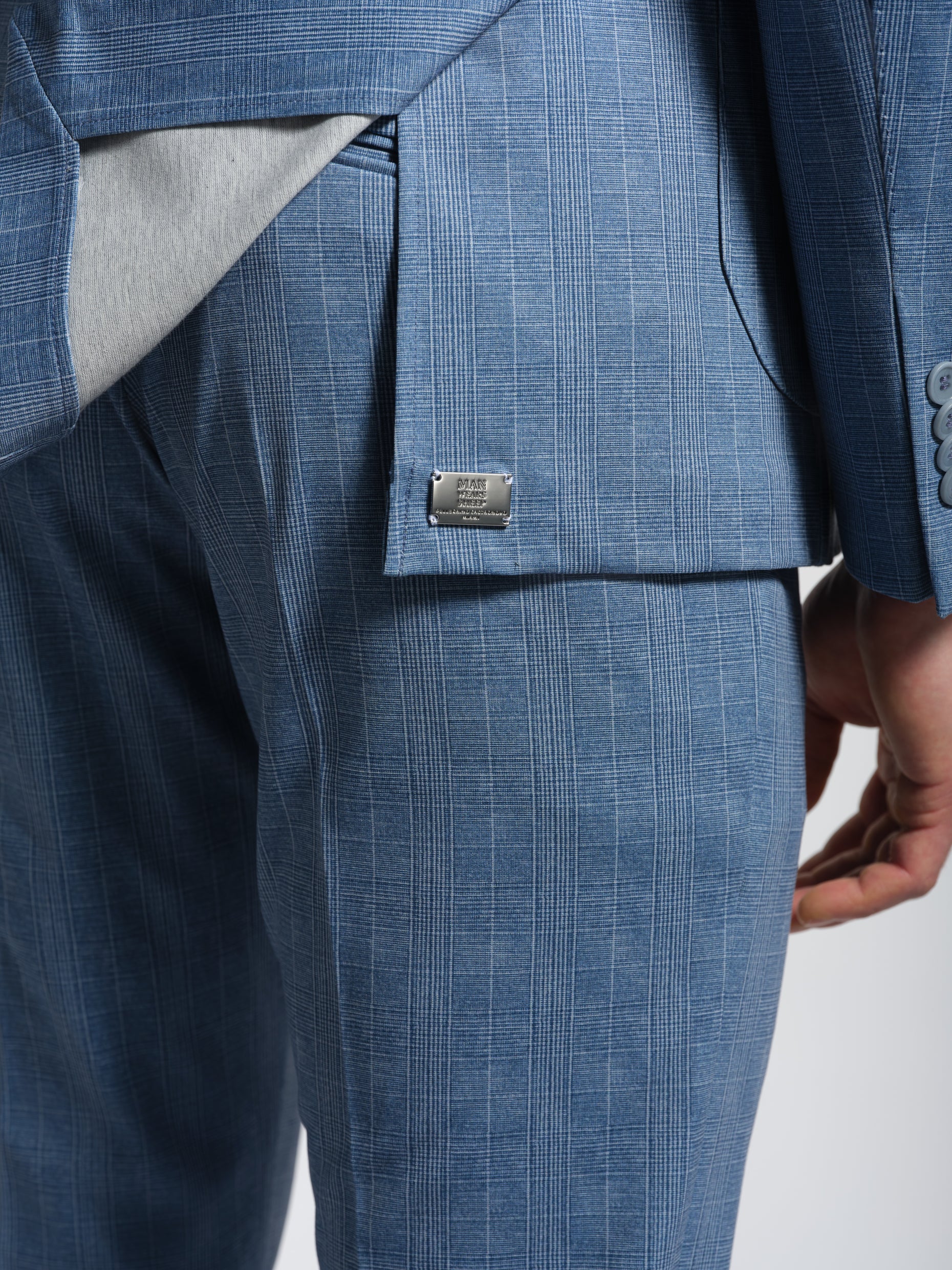 Close-up of a blue checkered suit with a metal brand label