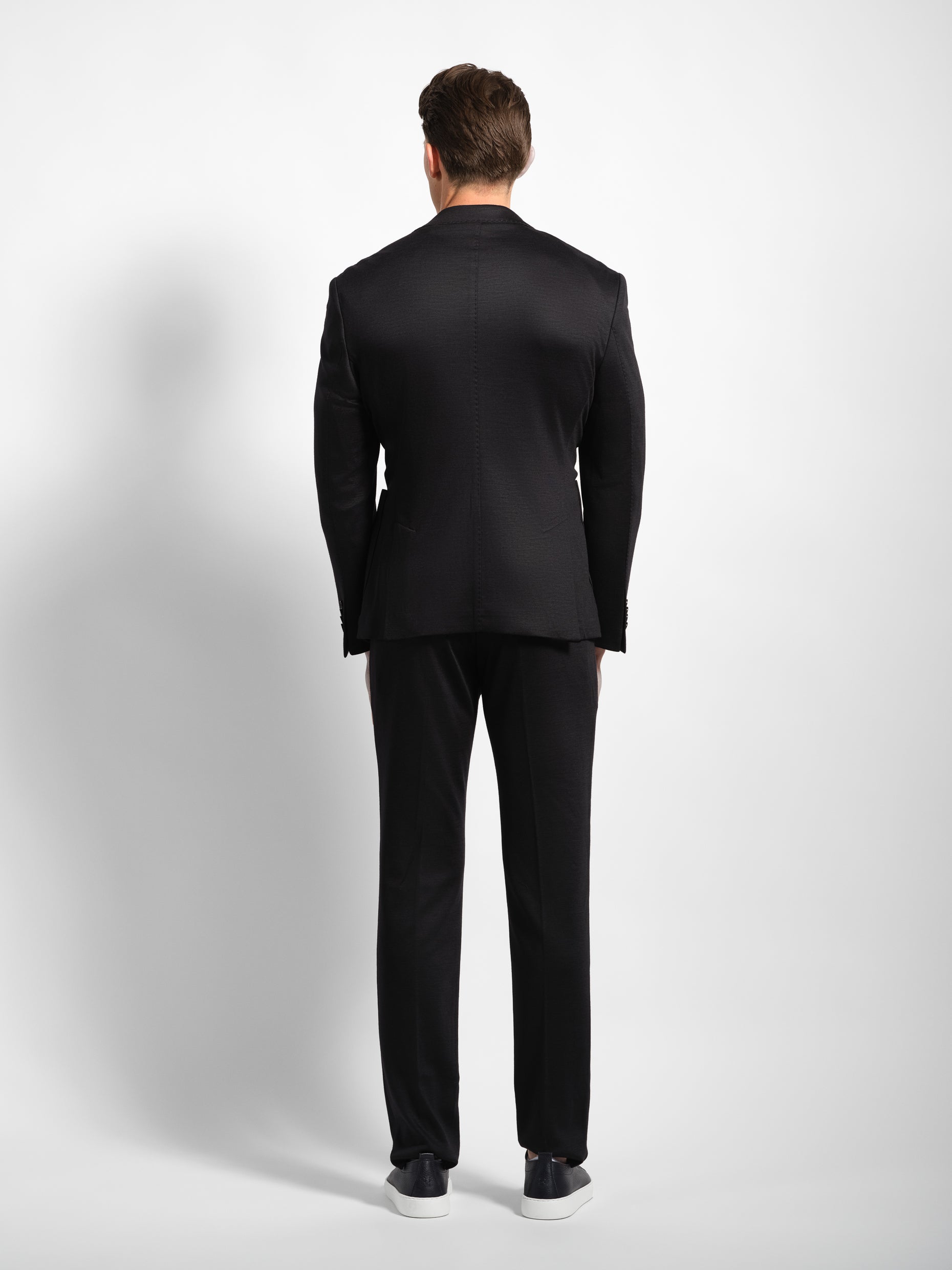 Man wearing a black jersey stretch suit back view