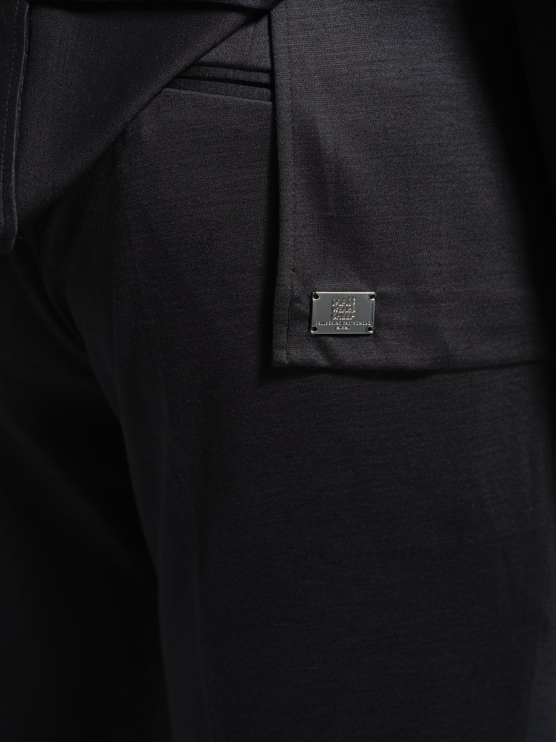 Close-up of a black jersey stretch suit jacket with a brand label