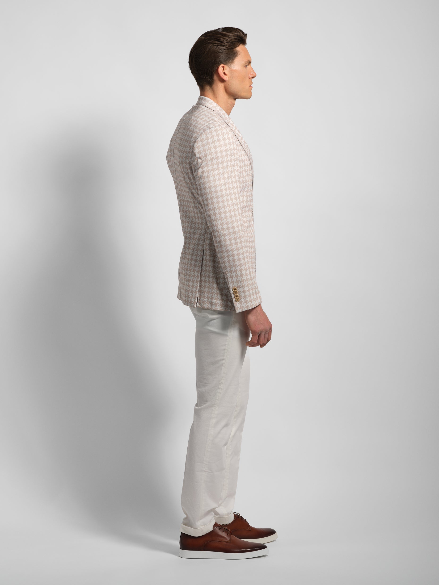 side view Man wearing a houndstooth beige jersey blazer white pants