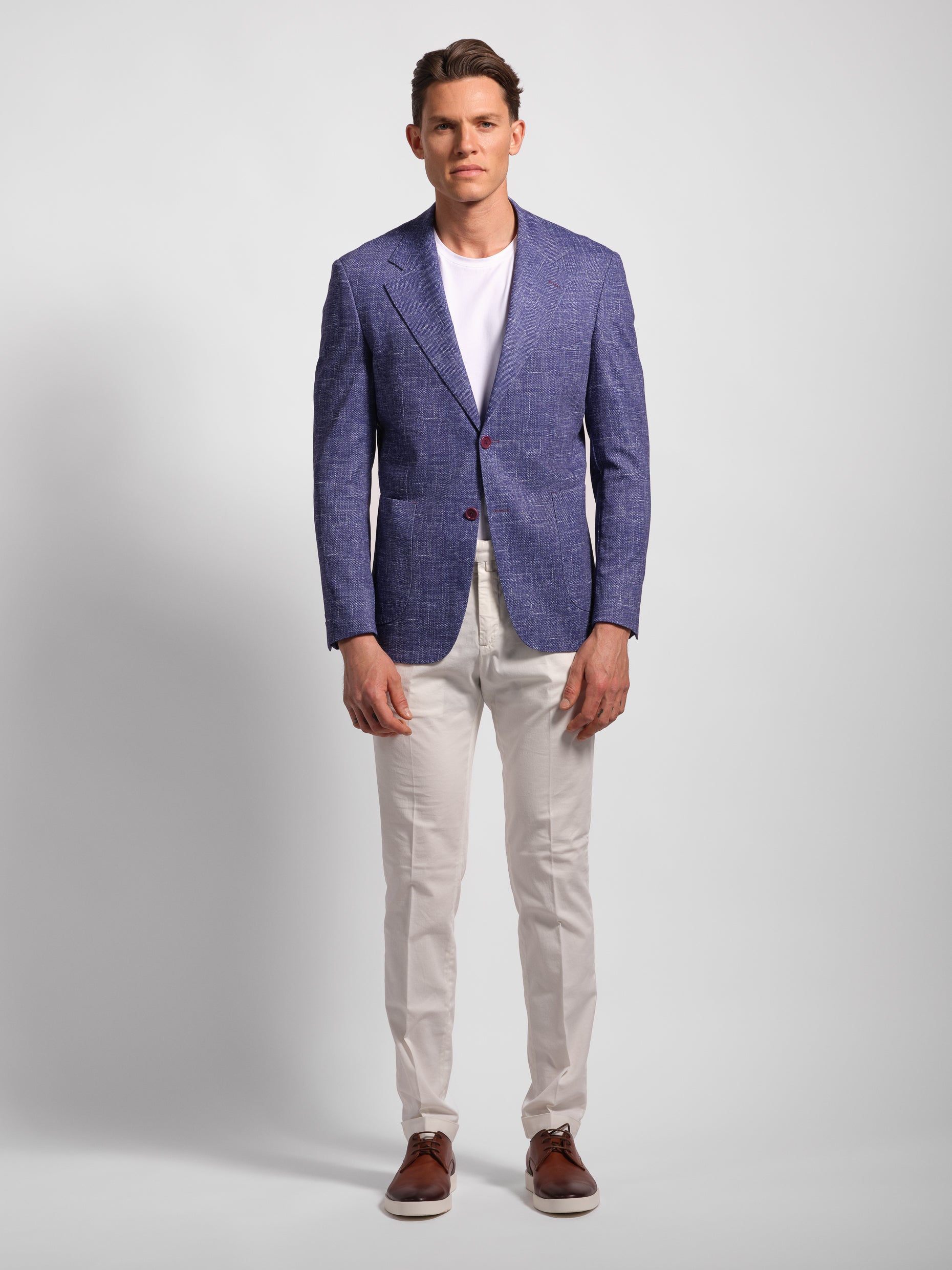 Man wearing a purple blazer over a white shirt and white pants with wide notch lapels and patch pockets