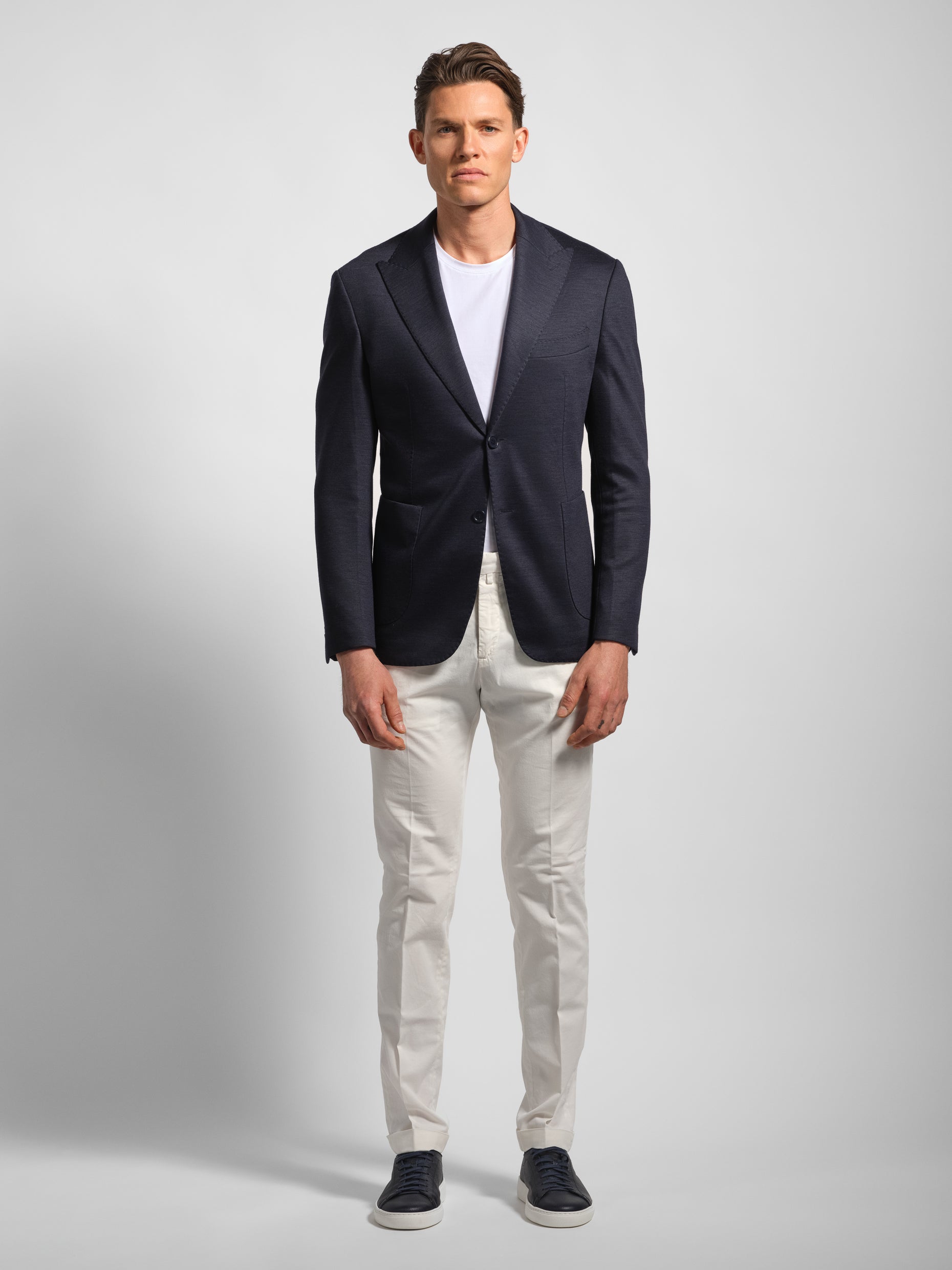 Man wearing a navy blazer, white shirt, and white-colored pants