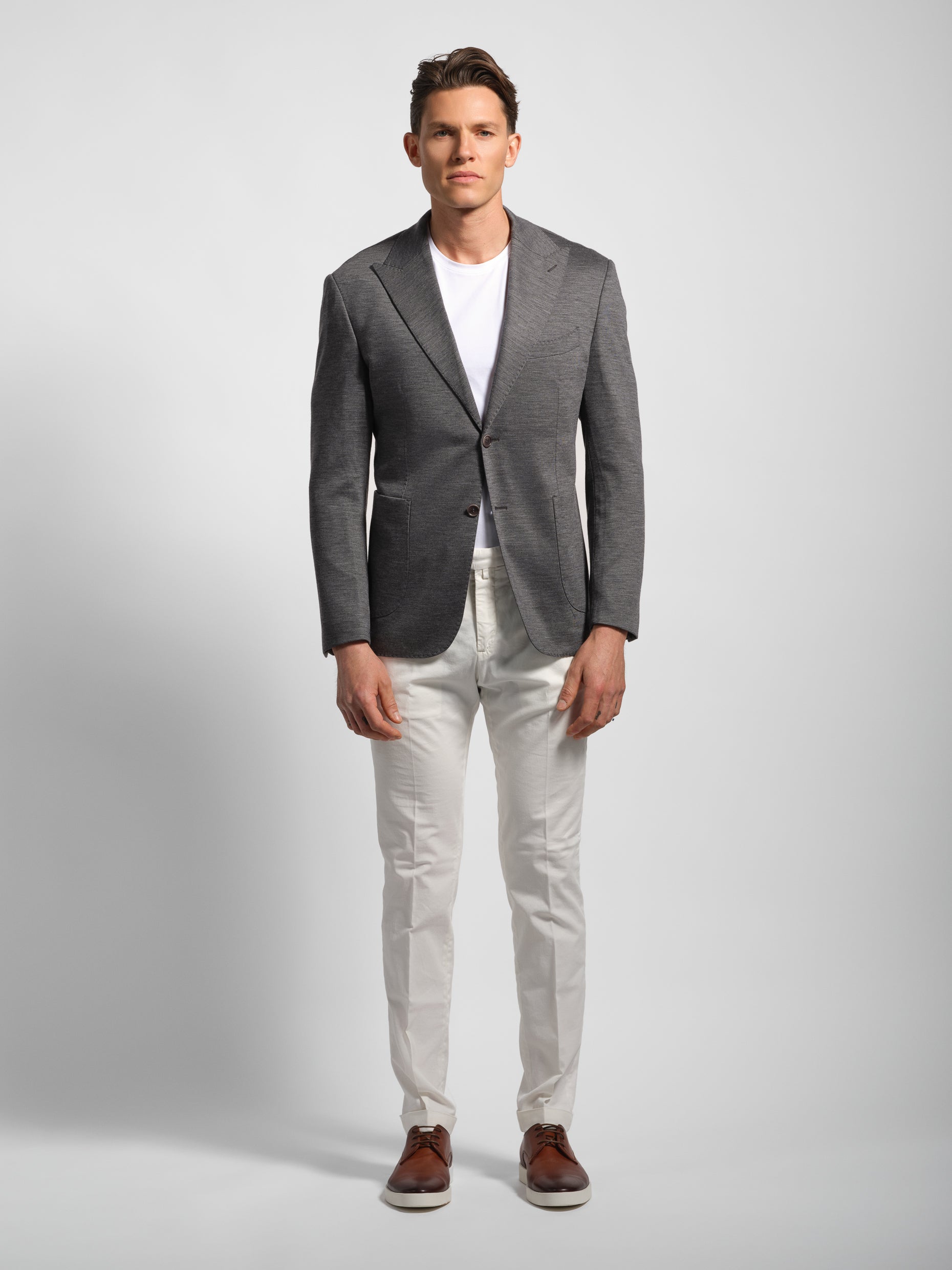 Man wearing a gray blazer, white shirt, and white colored pants