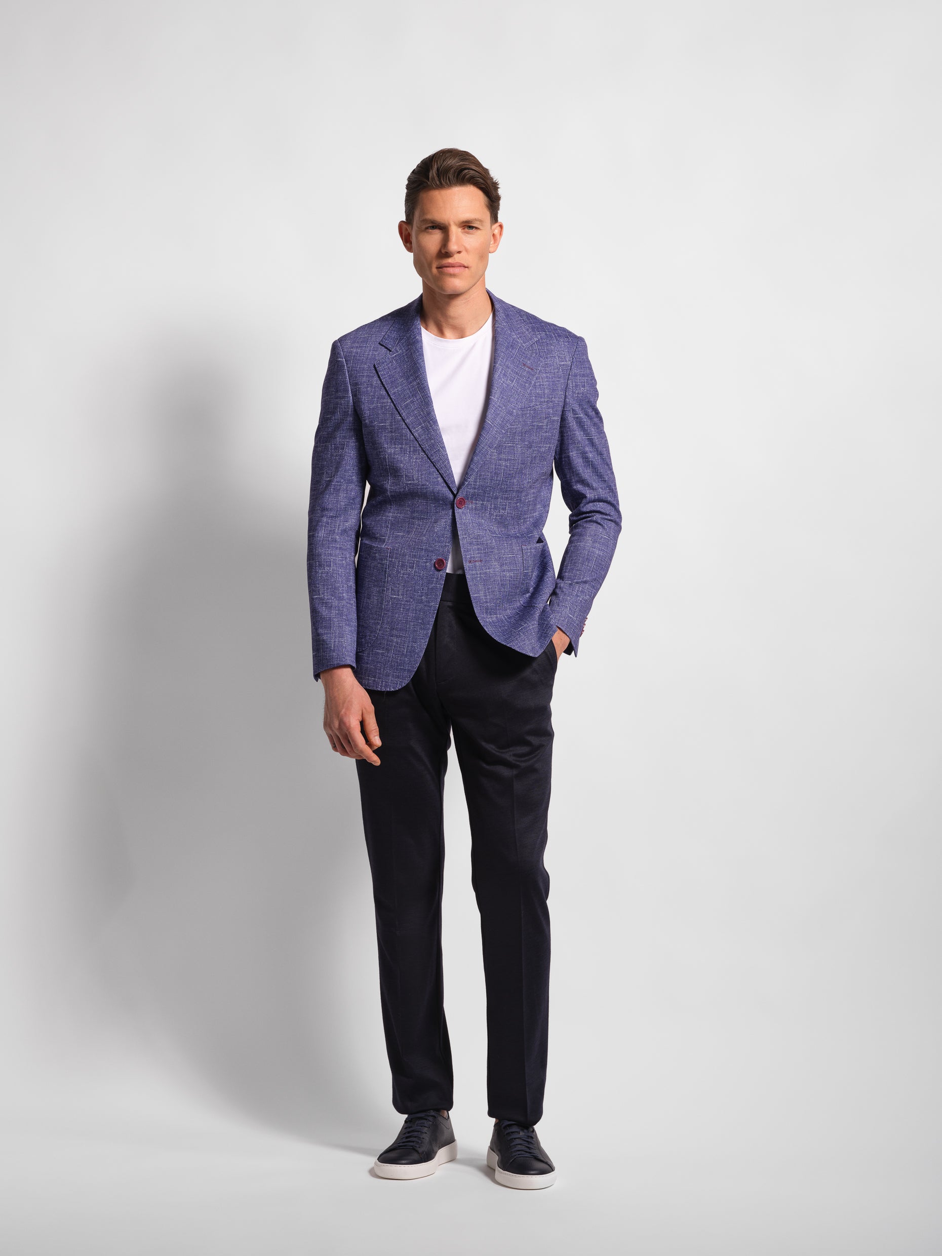 Man wearing a stretch jersey purple blazer over a white shirt and Navy pants with wide notch lapels and patch pockets model