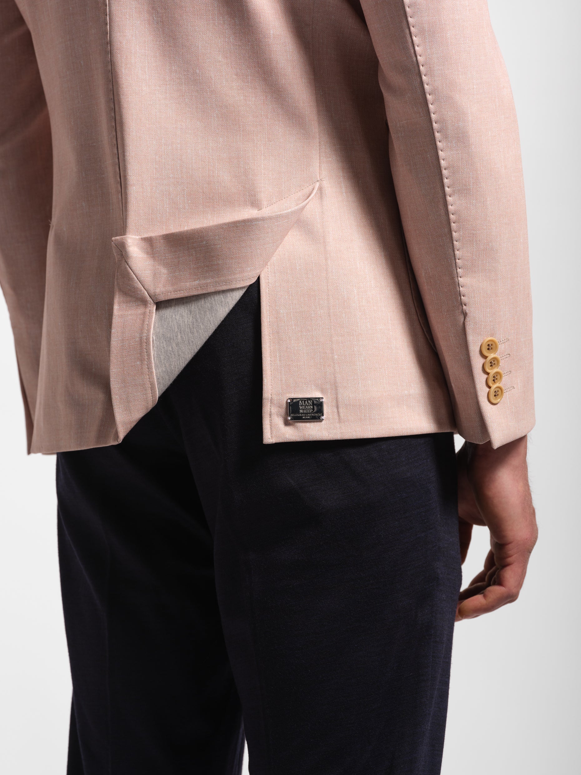 Close-up of a beige blazer with four buttons on a white background metal logo