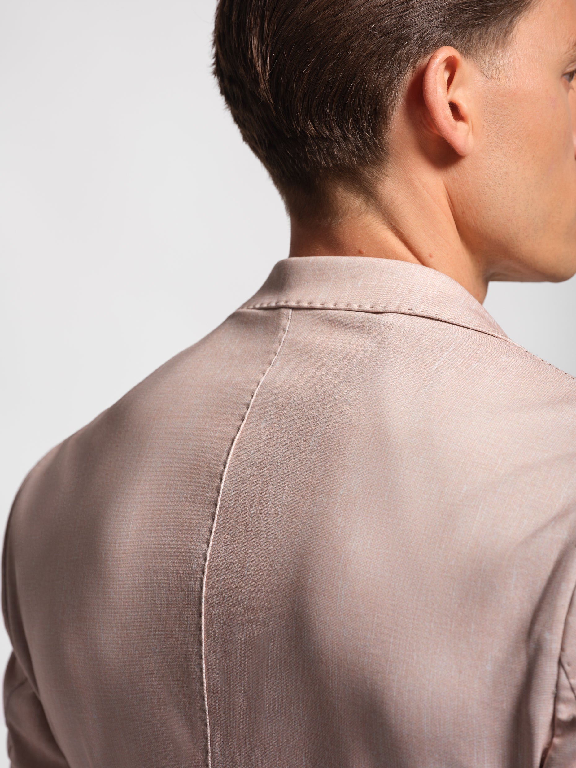 Close-up of a person wearing a light coral stretch and comfortable blazer with top stiching
