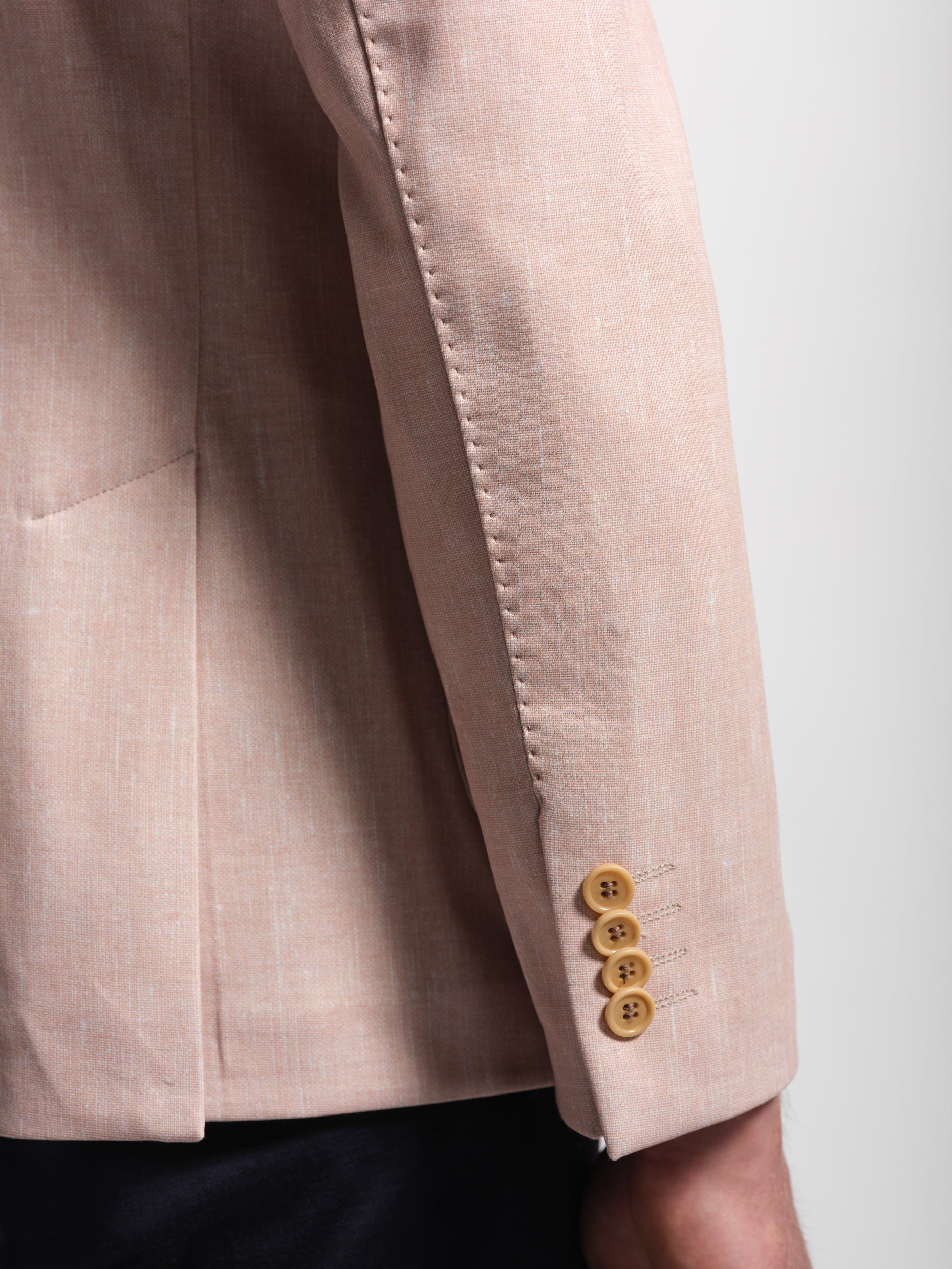Close-up of a coral blazer with four buttons on a white background showing topstitch and a stretch and comfortable jacket
