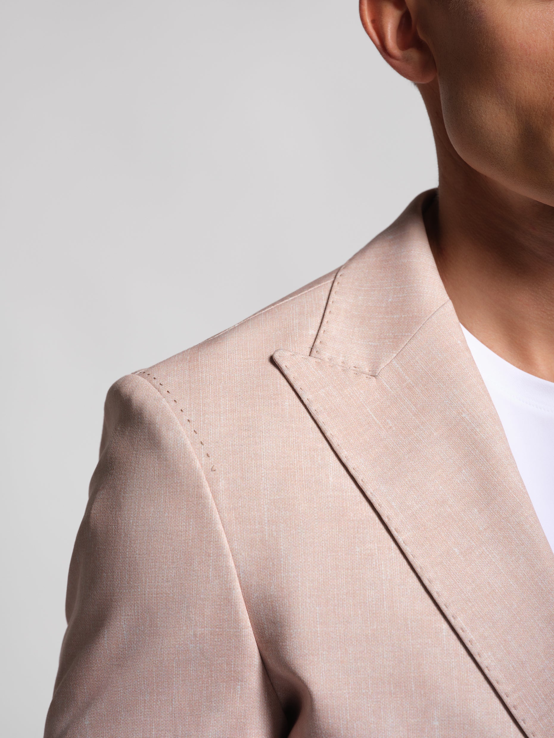 a stretch and comfortable Beige blazer worn by a person on a light gray background with peak lapel and topstiching