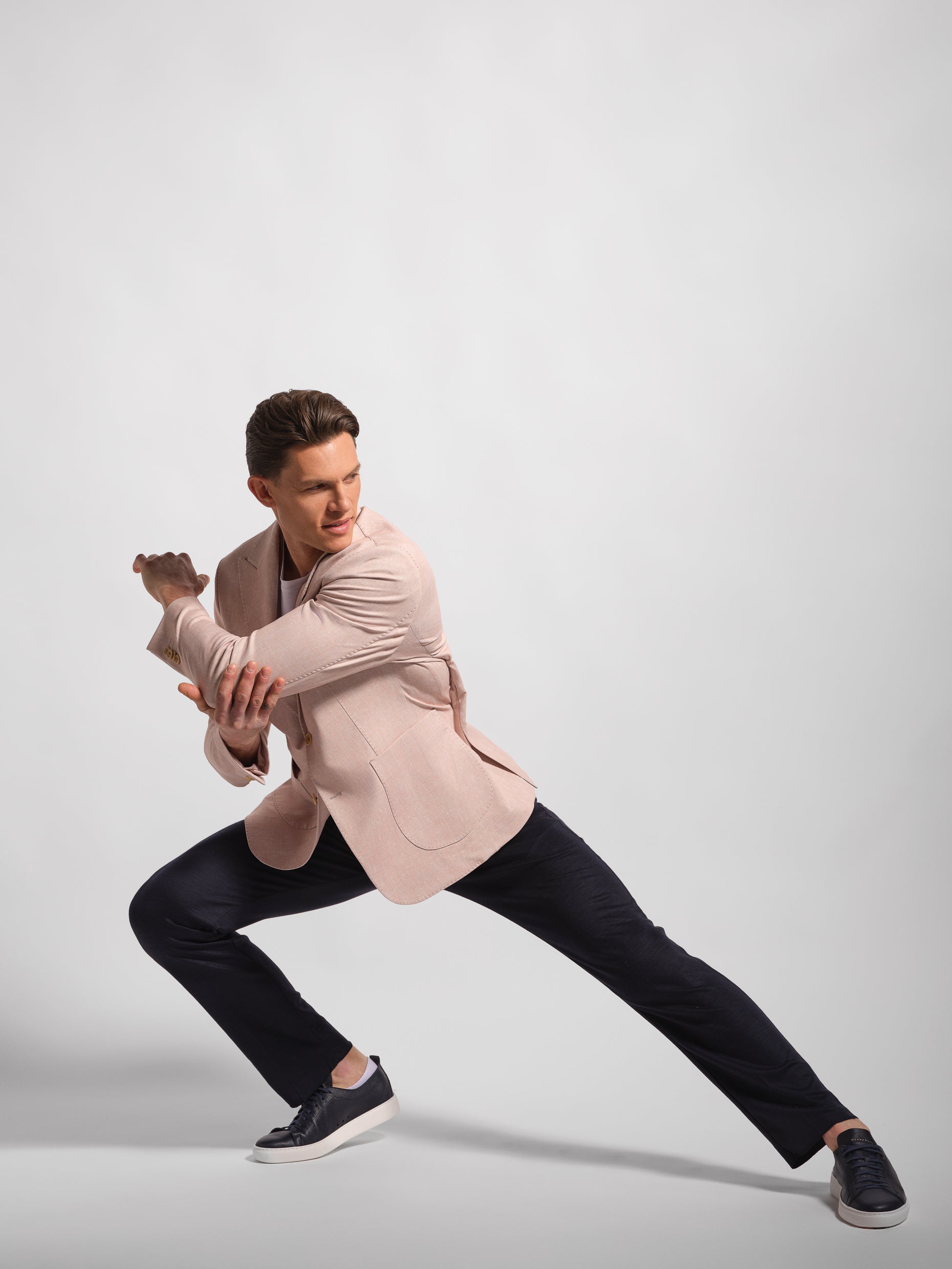 Man in a coral pink jacket and navy pants posing against a light gray background comforatble jacket