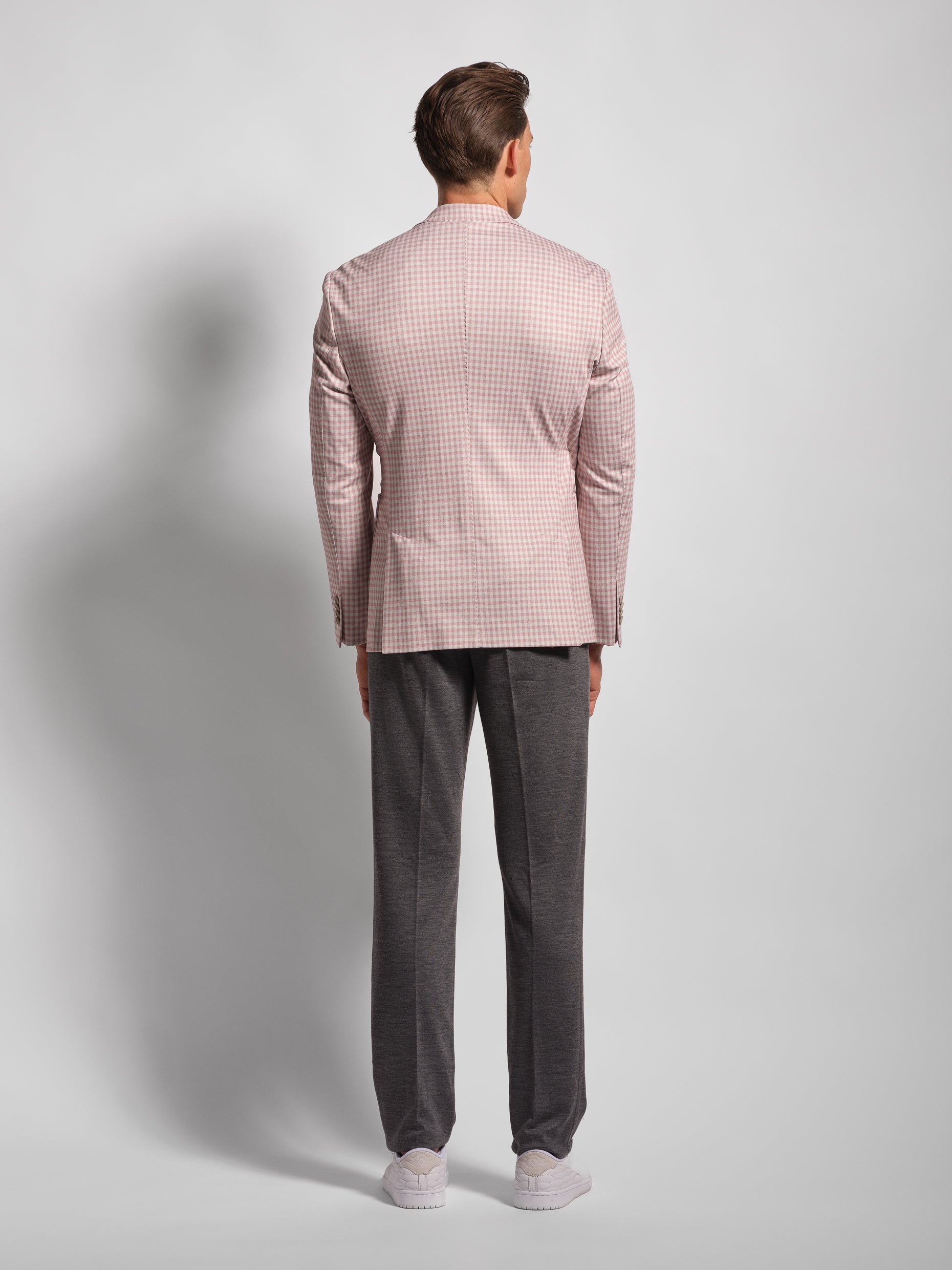 Man wearing a pink checkered blazer and gray pants back view