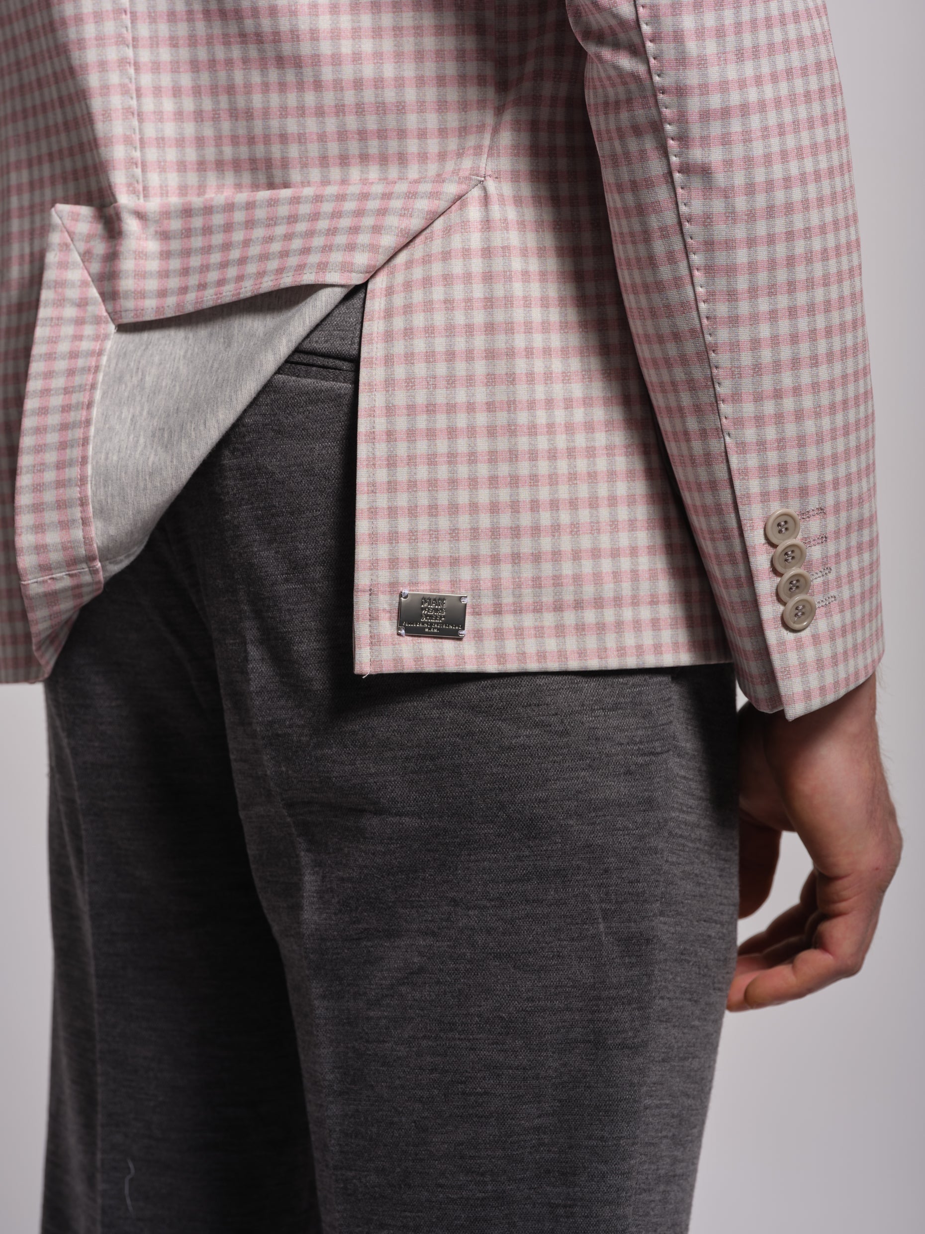 Person wearing a pink and white checkered metal logo grey pants and top stitch