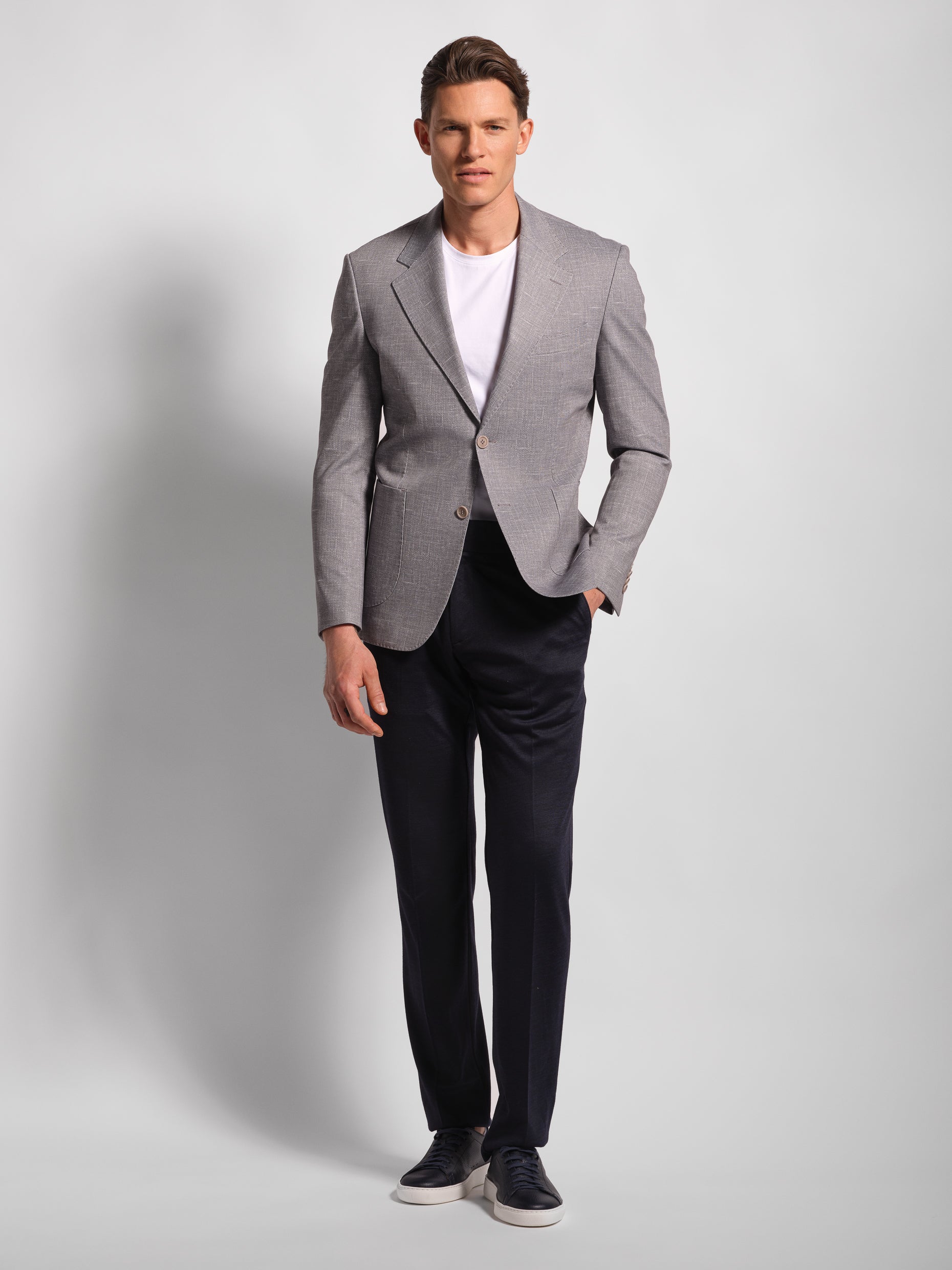 Man wearing a gray comfortable blazer, white shirt, and black pants on a light gray background