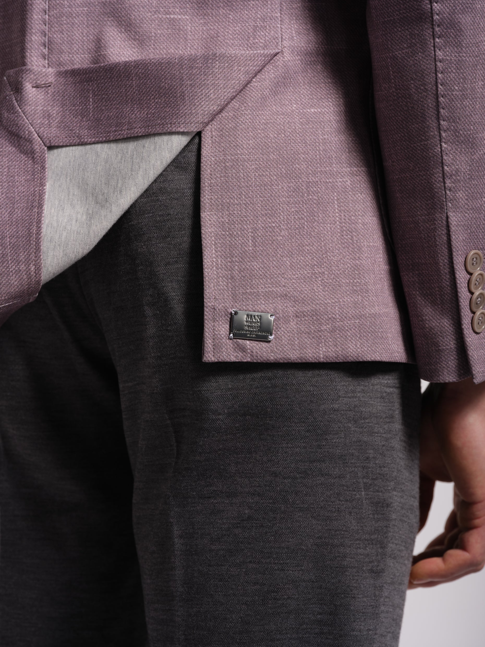 Close-up of a person side vents wearing a purple blazer with a visible metal brand label.