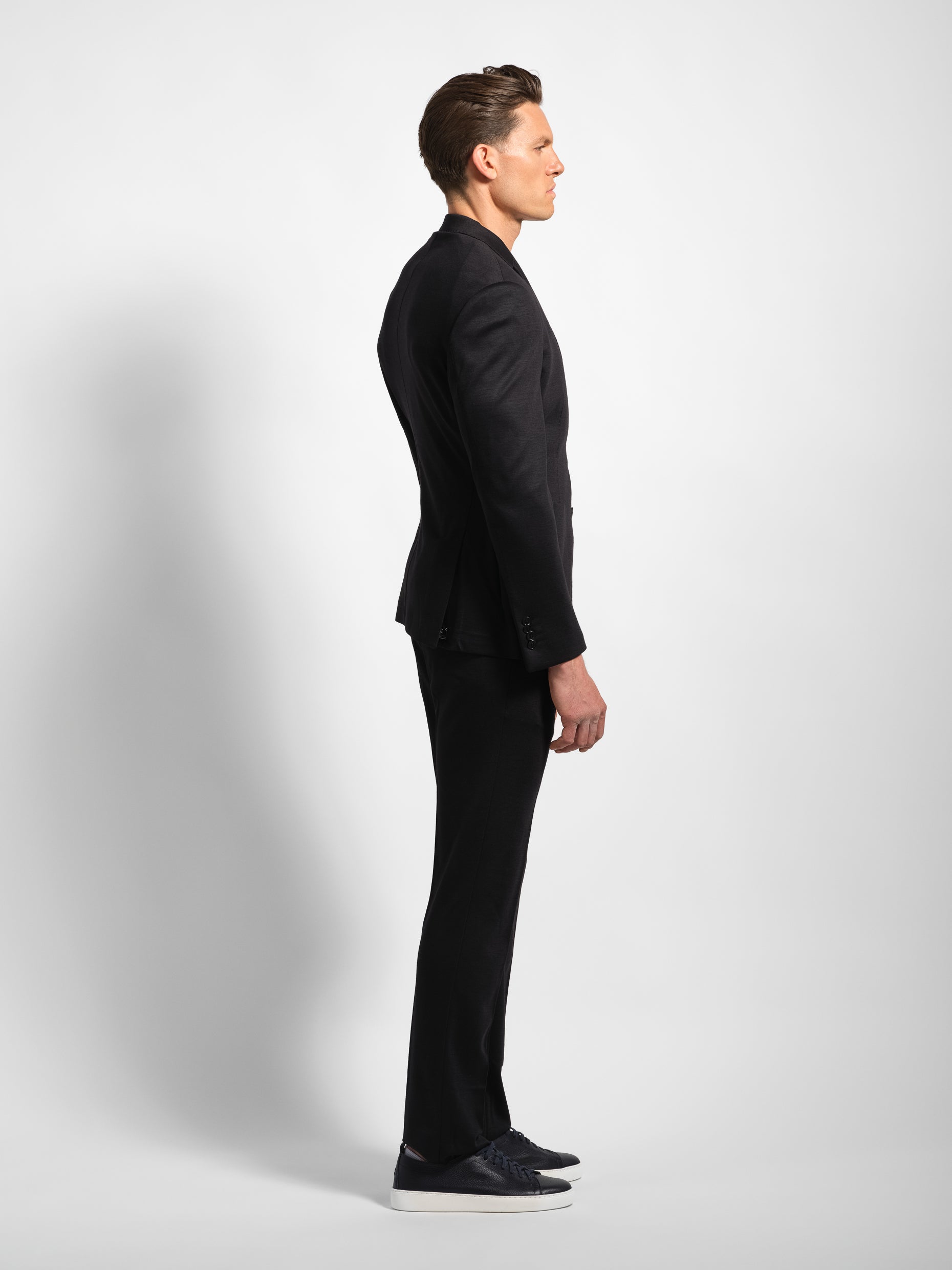 Man wearing a black jersey stretch suit side view