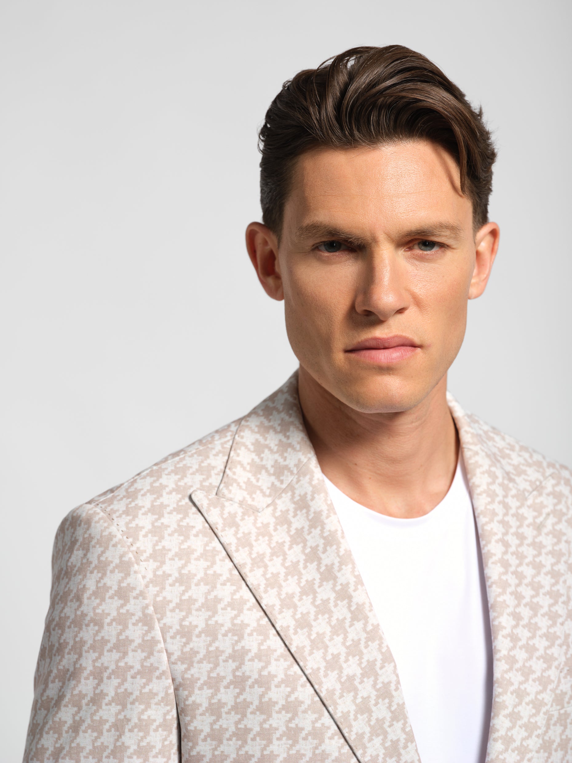 close up of man wearing a Houndstooth blazer over a white shirt 