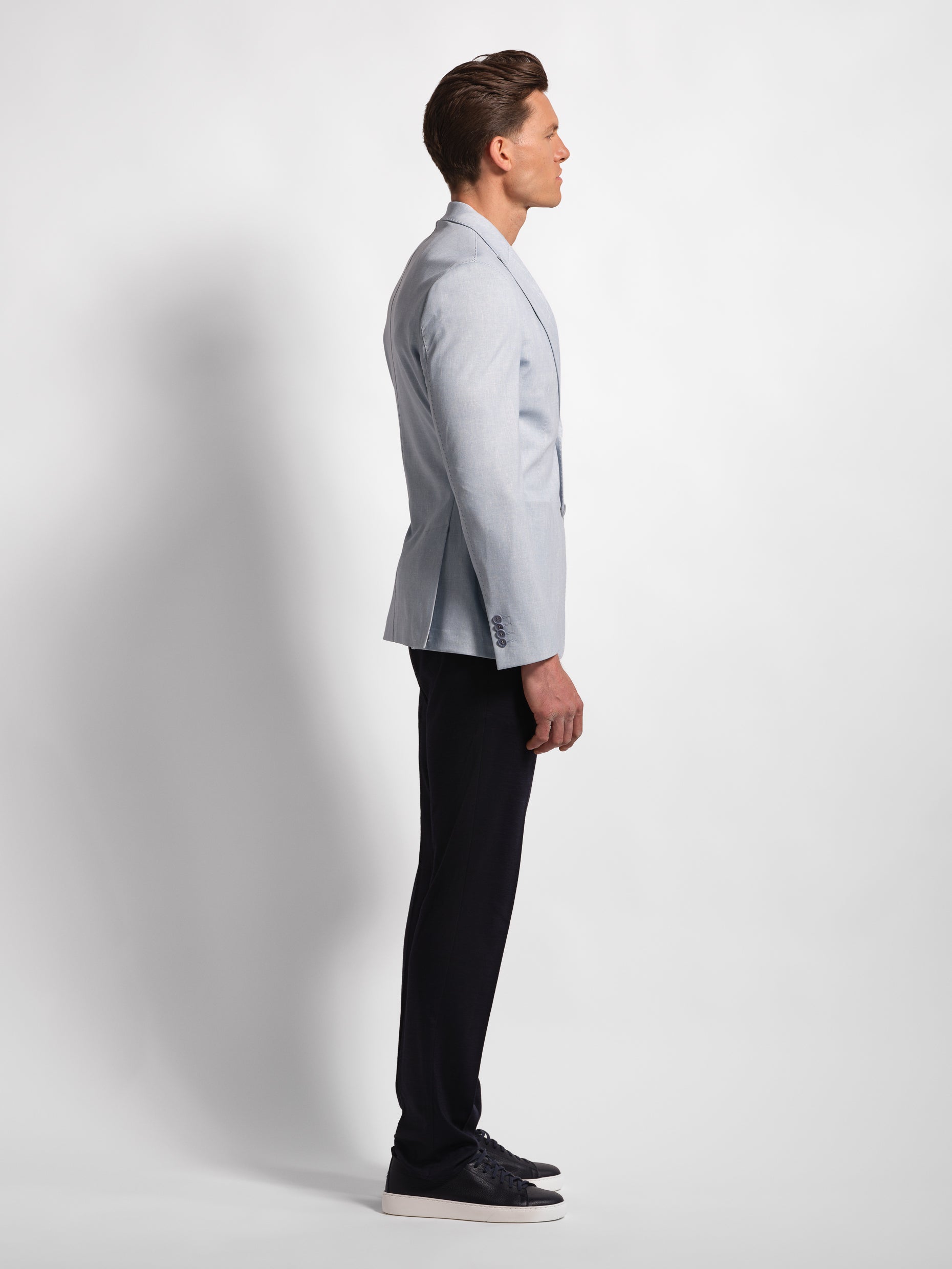 Man wearing a light blue blazer and Navy pants on a white background