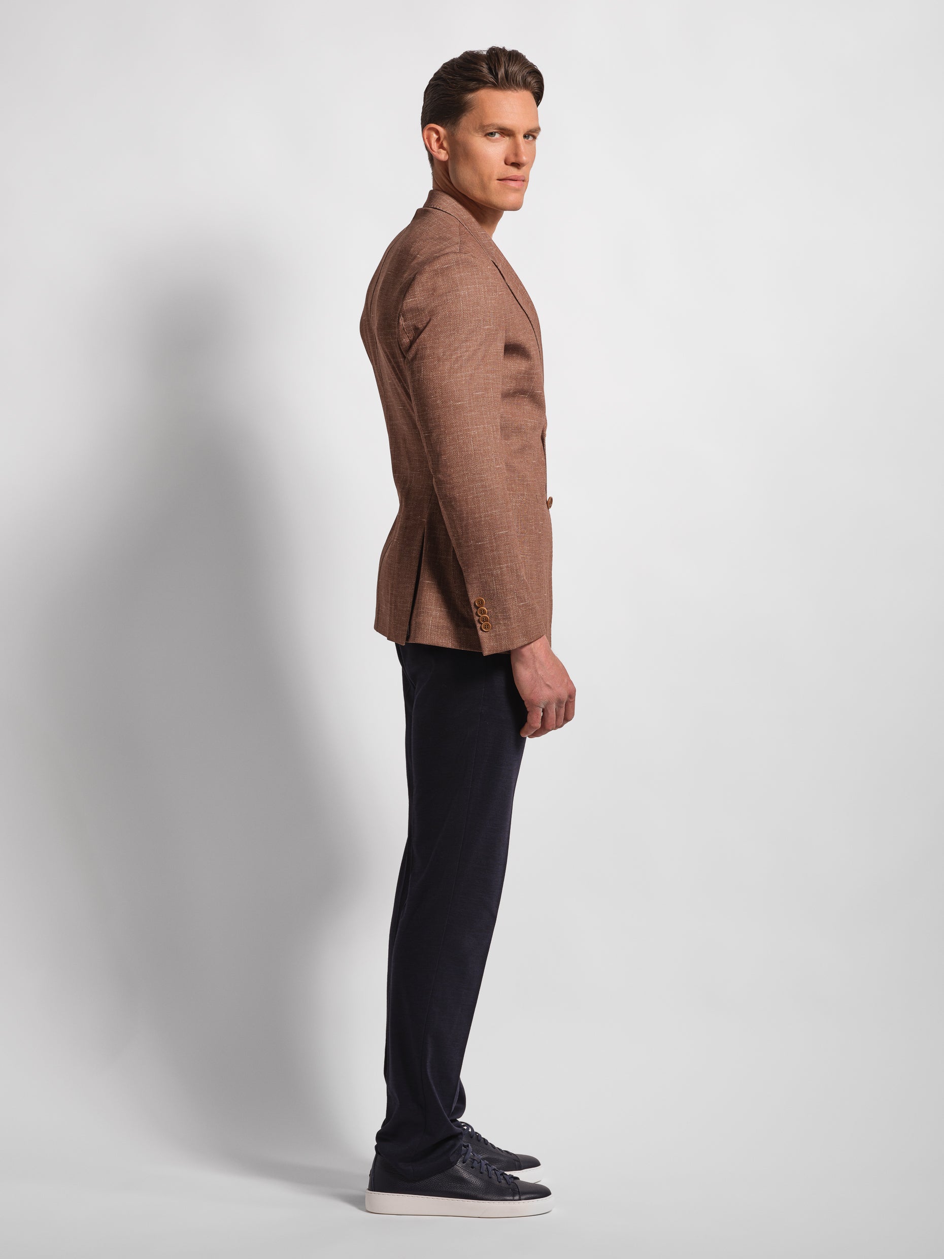 profile Man in a stretchy, comfortable jersey brown blazer over a white t-shirt with navy pants 