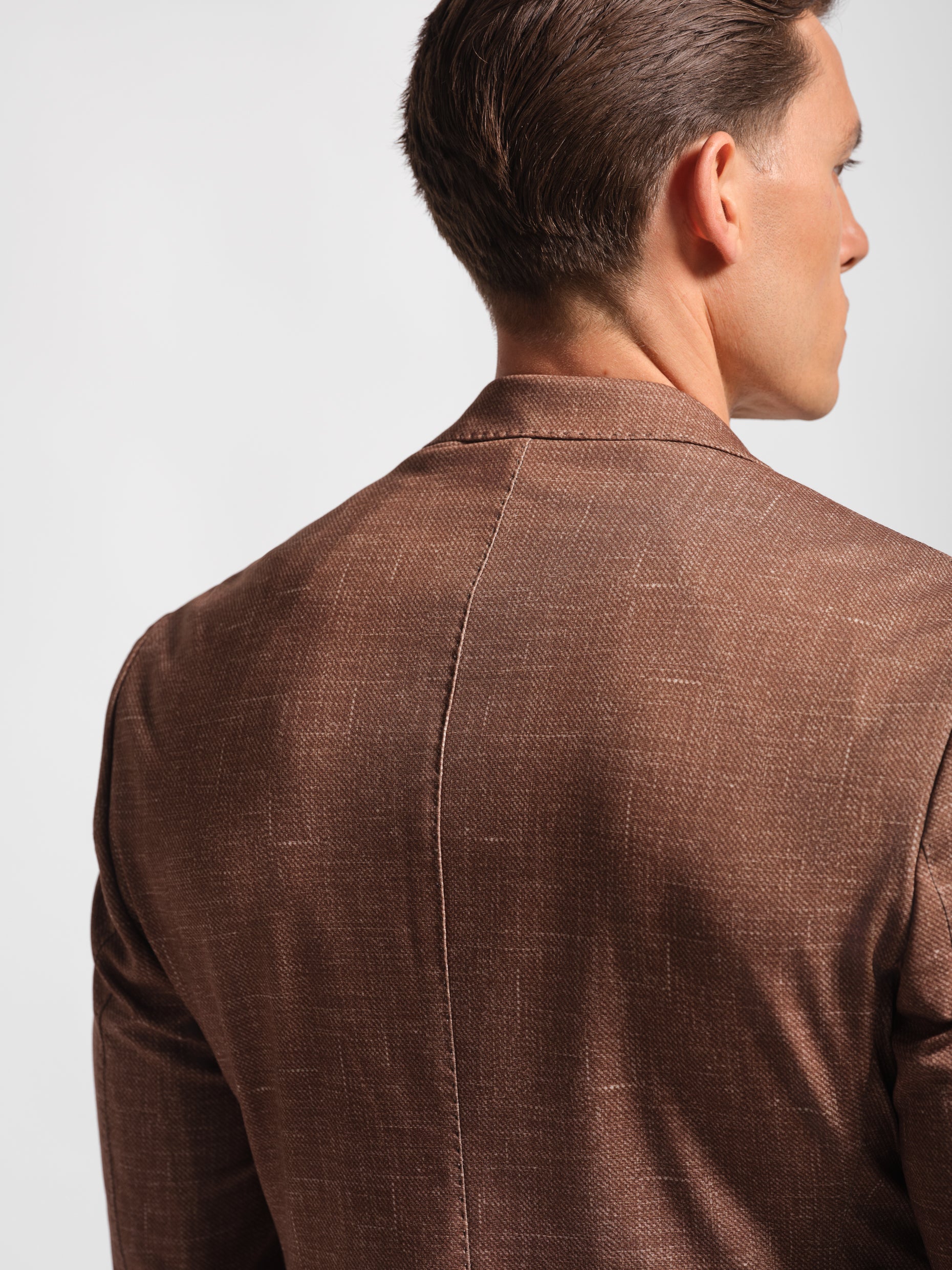 Back of Man in a stretchy, comfortable jersey brown blazer over a white t-shirt with navy pants 2 button