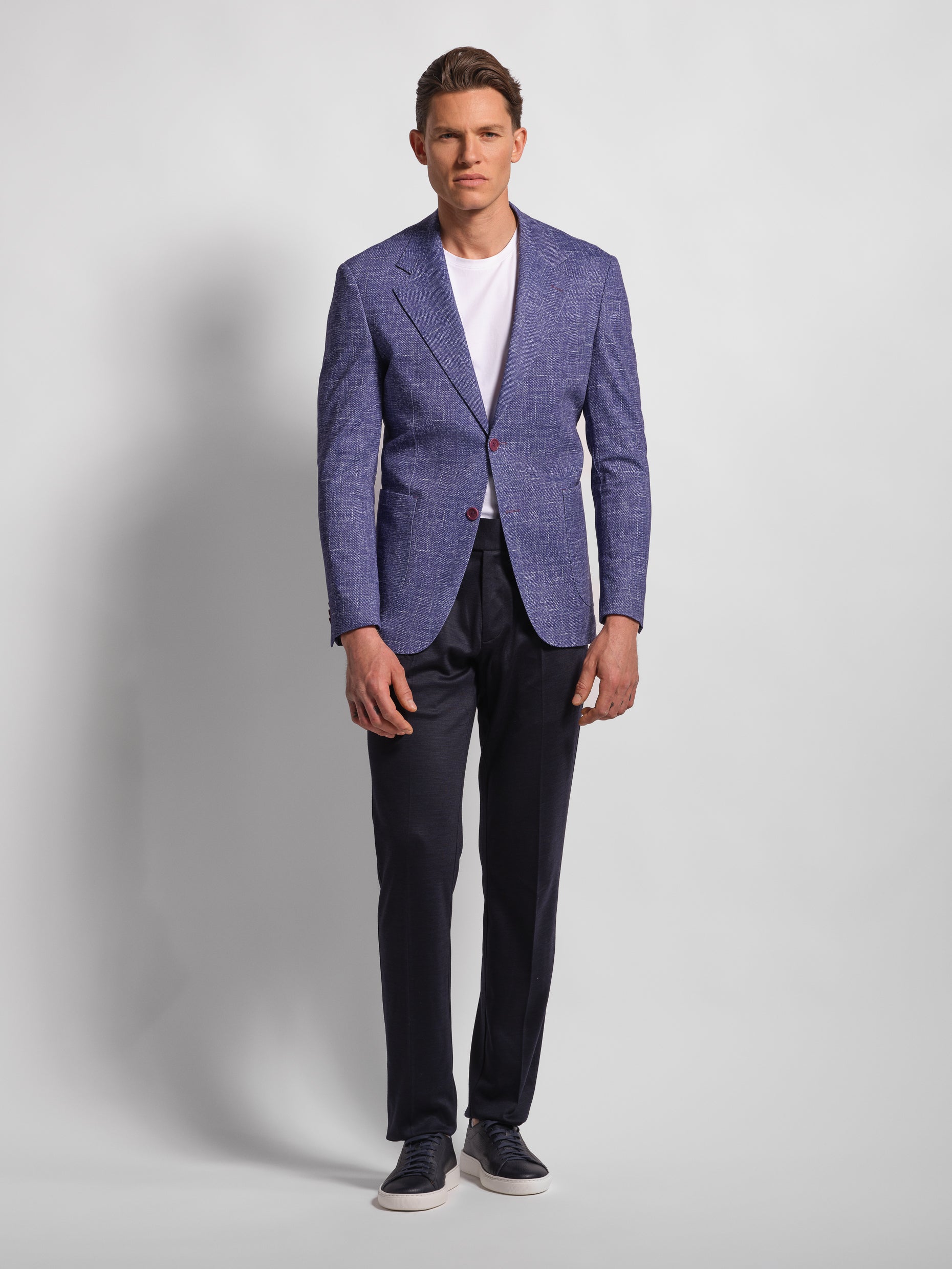 Man wearing a purple blazer over a white shirt and Navy pants with wide notch lapels and patch pockets