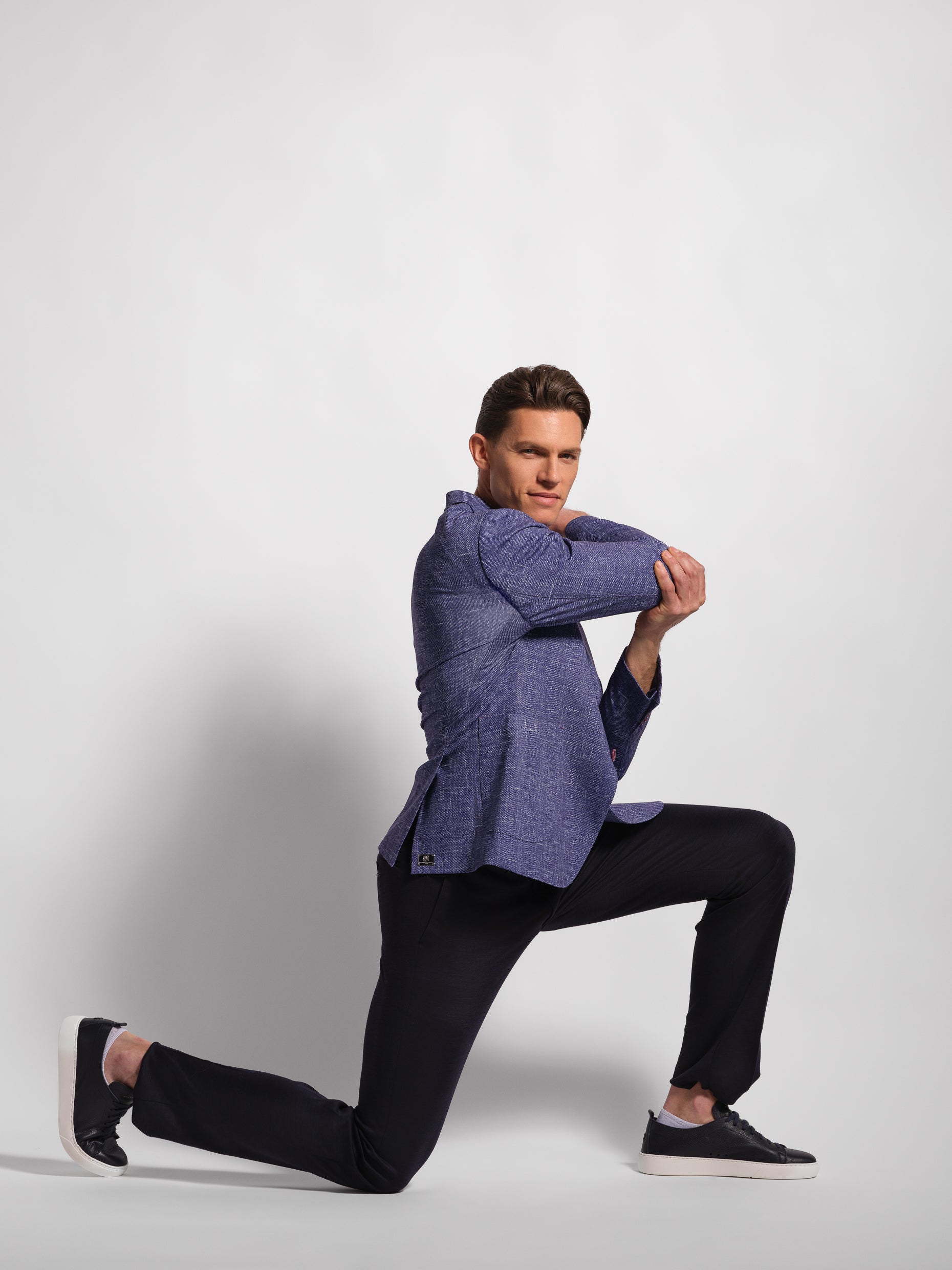 Man wearing a purple blazer over a white shirt and Navy pants with wide notch lapels and patch pockets showing stretch and comfort