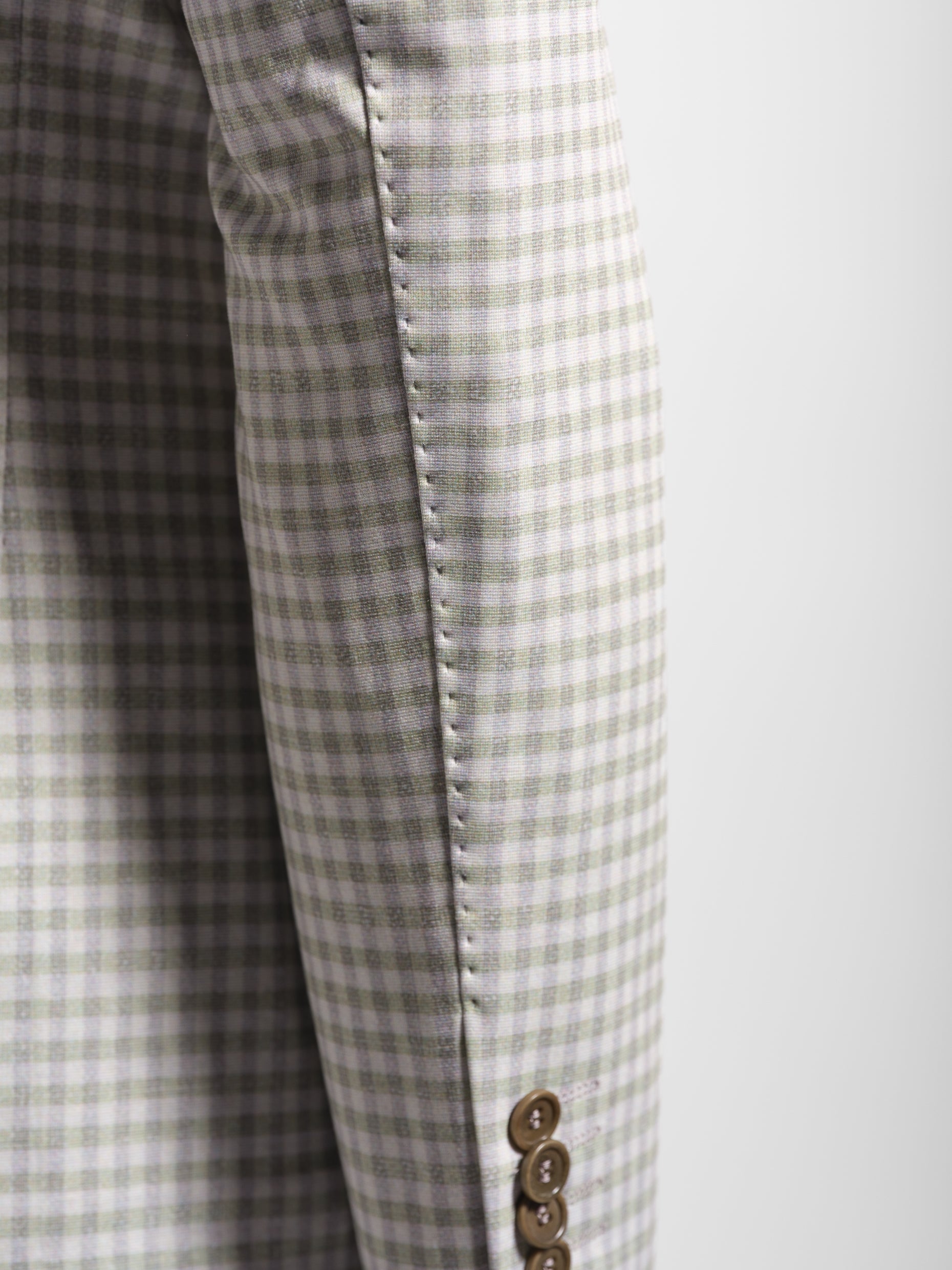 Close-up of a green checkered fabric with a button and top stitch 